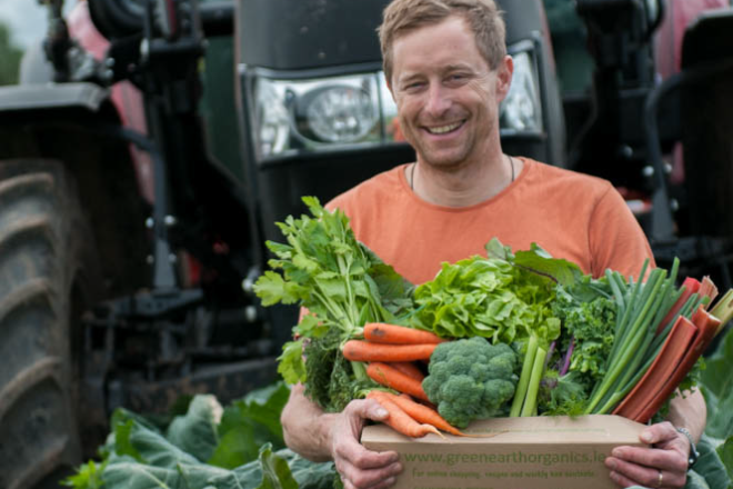 farmer with vegetables in front of tractor
